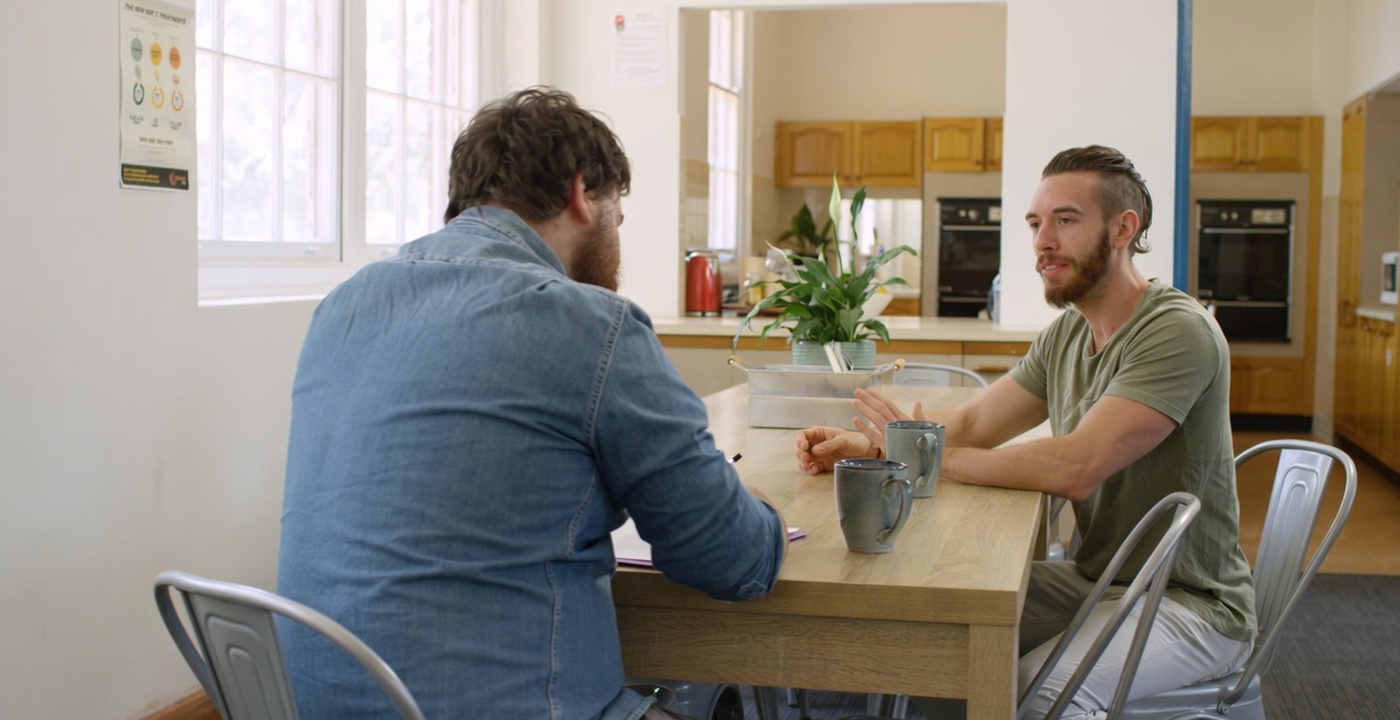 Two people talking together at a table in a WHOS community room.